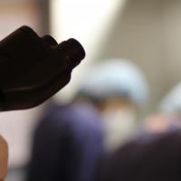 Closeup of microscope with physicians in background.